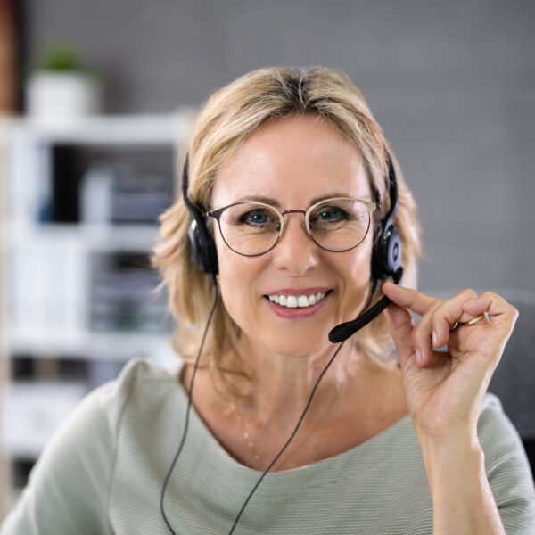 Business Service Agent With Headset At Computer On Phone